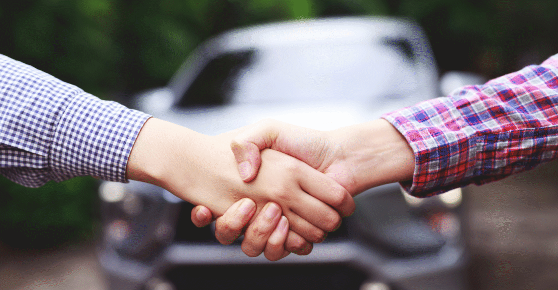 Two people shaking hands over a car rental agreement in Morocco.