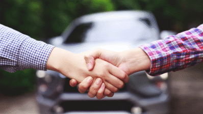 Two people shaking hands over a car rental agreement in Morocco.